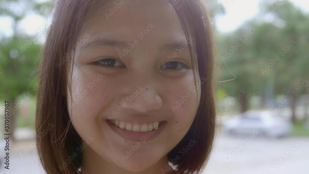 Slow motion close up shot of a smiling Asian teen girl has short brown hair is standing in the evening. Slow motion close up shot of a smiling Asian teen girl has short brown hair is standing in the evening.