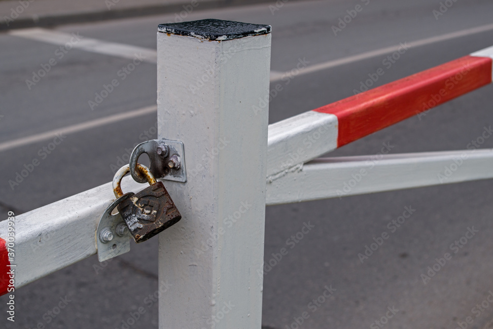 Φωτογραφία Support post and extreme part of horizontal metal boom barrier, painted in red and white stripes against background of blurred gray asphalt and road markings