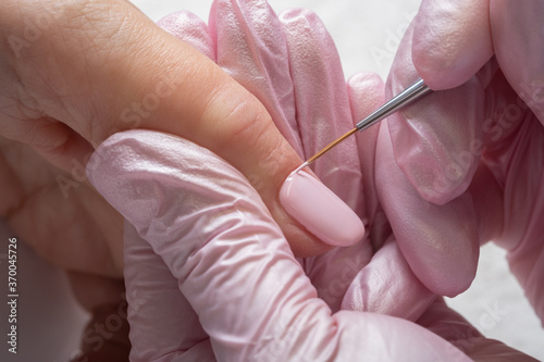 Close up of a woman hand with pink nail polish. Woman in nail salon receiving manicure by beautician. Manicure process in beauty salon, close up. Close up of a woman hand with pink nail polish. 