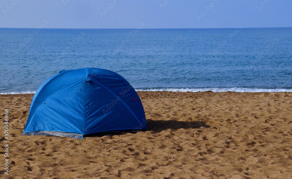 Tourist rest in a tent on the sandy seashore. rest by the sea in a blue tent