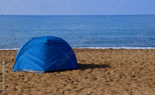 Tourist rest in a tent on the sandy seashore. rest by the sea in a blue tent © Asgat
