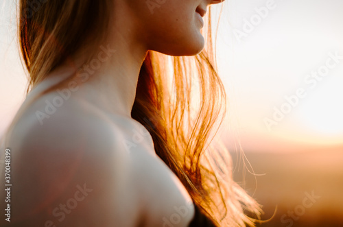 Close up details of a young caucasian woman with hair bathed by golden light