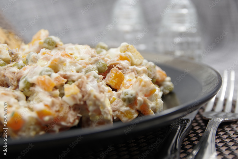 Tuna salad in black plate. Ingredients: tuna, carrots, eggs, onion, canned peas, croutons, mayonnaise Tuna salad in black plate. Ingredients: tuna, carrots, eggs, onion, canned peas, croutons, mayonnaise