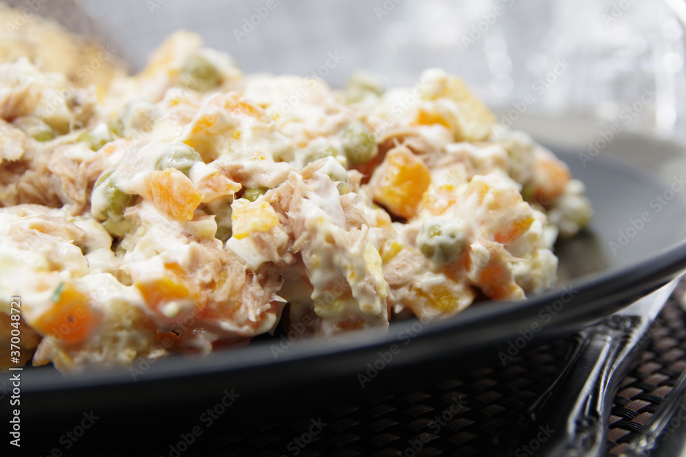 Tuna salad in black plate. Ingredients: tuna, carrots, eggs, onion, canned peas, croutons, mayonnaise Tuna salad in black plate. Ingredients: tuna, carrots, eggs, onion, canned peas, croutons, mayonnaise