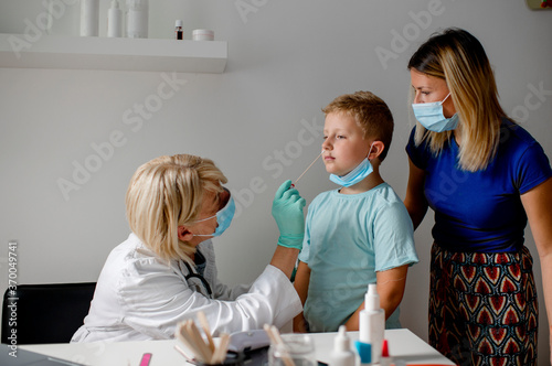 Doctor taking a sample from a boy's nose using a cotton swab