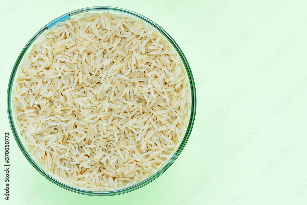 Basmati rice groats in a glass bowl on a light green background. Dry basmati rice background. Basmati rice texture. A product of proper nutrition. Basmati rice grain background texture.Vegetarian food Basmati rice groats in a glass bowl on a light green background. Dry basmati rice background. Basmati rice texture. A product of proper nutrition. Basmati rice grain background texture.Vegetarian food