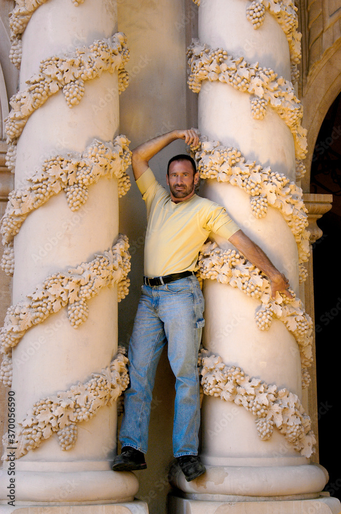 A handsome model in front of a very ornate column posing in as a Greek God.  
