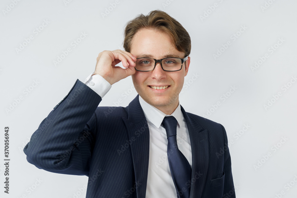 Portrait of a businessman in a blue suit, who adjusts his glasses. White background.