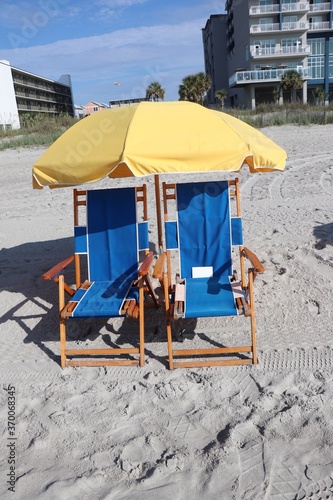 Umbrella and lounging chairs on the beach with hotels in the background 