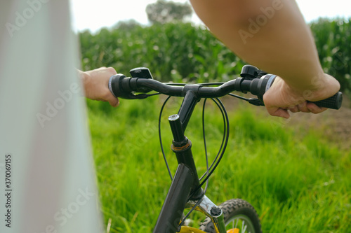 Male hands on a background of grass, bike, mountain handlebar. Brakes