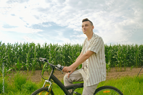 The guy on the background of the corn field sits on a bicycle