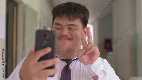 A fat Asian man wearing an office suit and wearing necktie and a white shirt is  thrillingly funny with a video call. photo