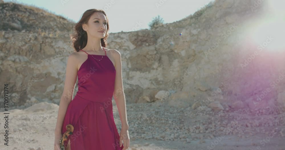 Portrait of pretty woman with violin in hand looks at the sky and down outdoors Portrait of pretty woman with violin in hand looks at the sky and down outdoors