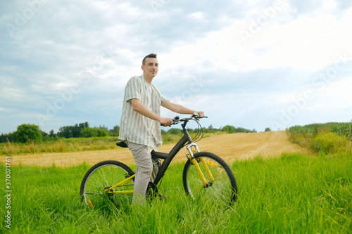 A man on a mountain bike. A fashionable guy came to nature in the field.