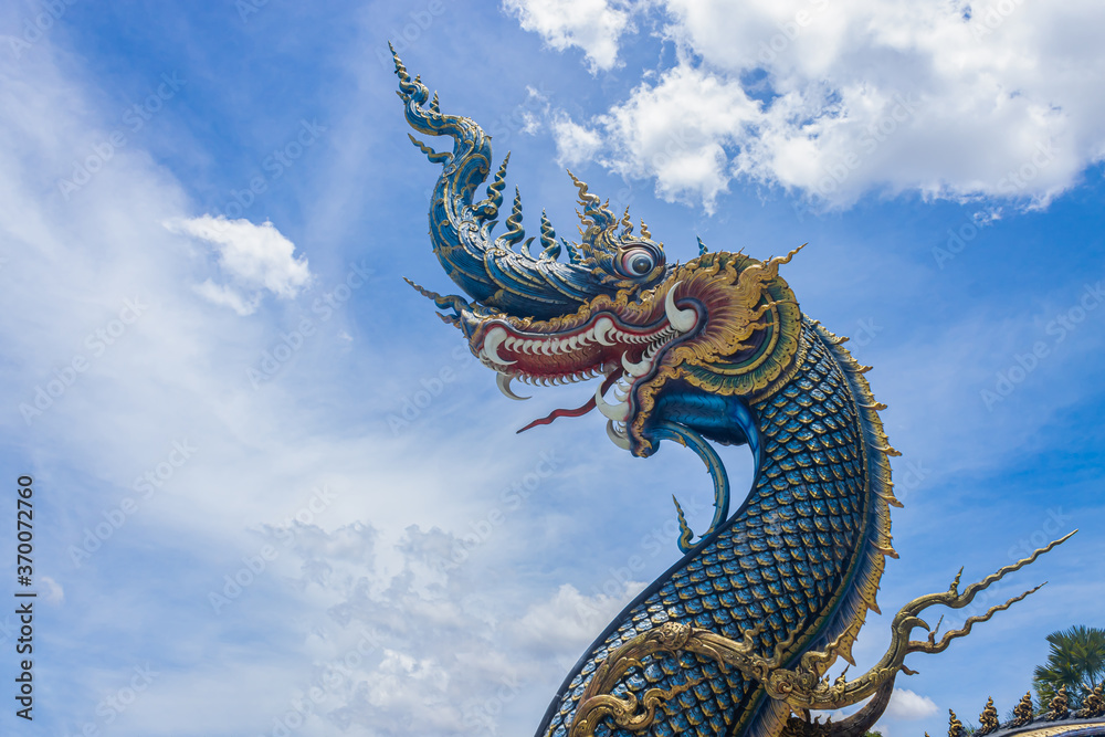 Fototapeta premium Chiangrai, Thailand - June 7, 2020: Blue Serpent or Naga on Blue Sky Background with Natural Light in Wat Rong Suea Ten Temple at Chiangrai Thailand