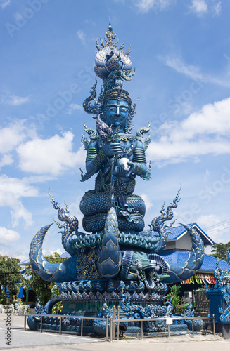 Chiangrai, Thailand - June 7, 2020: Blue God Statue Hold Lotus on Blue Sky Background with Natural Light in Wat Rong Suea Ten Temple