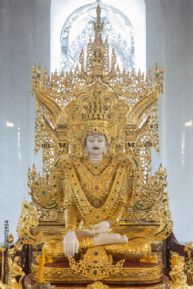 Fototapeta premium Phayao, Thailand - Dec 8, 2019: White God Statue Wear Gold Apparel in Portrait View with Natural Light in Thai Church at Analayo Temple in Thailand