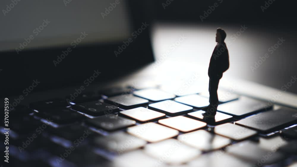 4K Video Close up zoom out shot mini businessman standing on notebook keyboard. Background for computer and technology.