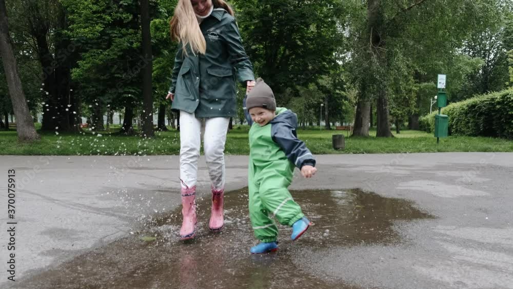 Family in a rainy park. Kids in a puddle. Child having fun outdoors. Family in a rainy park. Kids in a puddle. Child having fun outdoors.