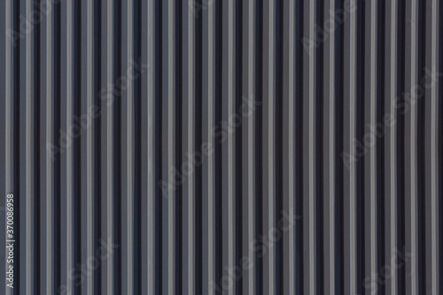 A corrugated fence of grey metal sheets. Texture of metal fence picket Profile decking. Internal primed side of a metal picket fence. Profiled metal.