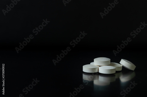 Pastillas blancas circulares sobre un fondo negro para mostrar información o productos