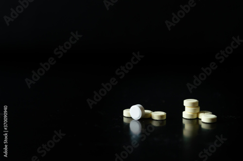 Pastillas o tabletas sobre un fondo negro para mostrar información o productos. pastillas blancas sobre un fondo negro.