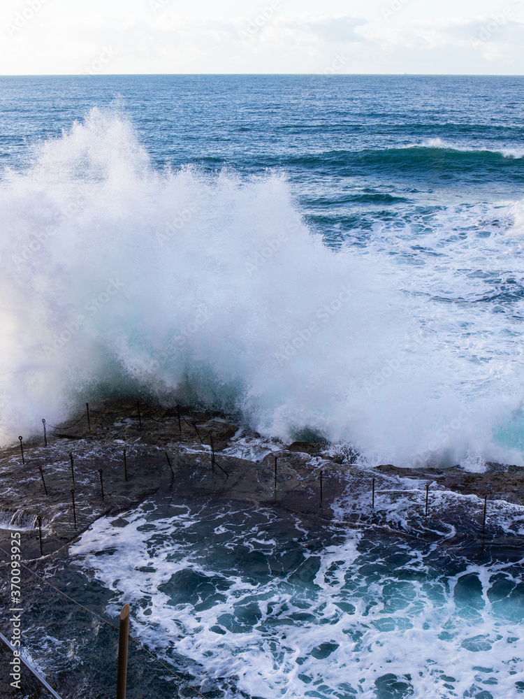 Obraz premium Wave crashing into the edge of rock pool.