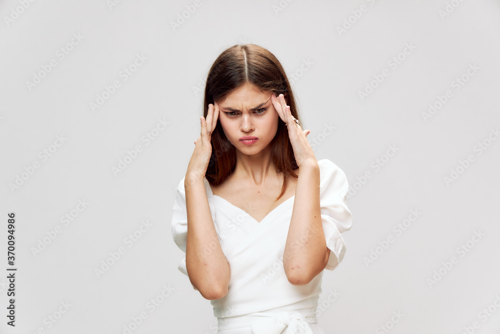 Dissatisfied woman headache hands near face white dress cropped view Dissatisfied woman headache hands near face white dress cropped view