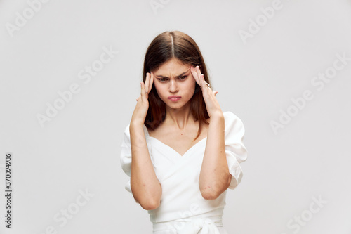 Dissatisfied woman headache hands near face white dress cropped view 