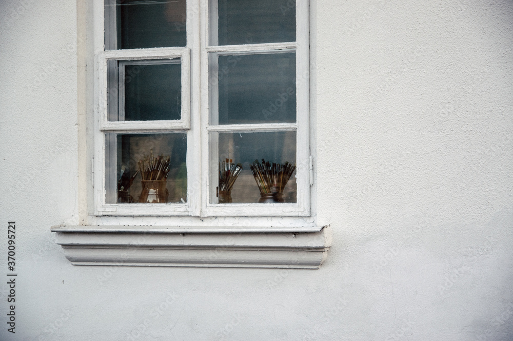 Białe okno za stojącymi na parapecie pojemnikami z pędzlami - obrazy, fototapety, plakaty 