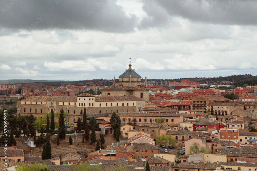 Urban texture. Cityscape. View of the ancient buildings and houses in the city of Toledo, Spain, under a cloudy sky. The Primate Cathedral of Saint Mary dome  in the background. 