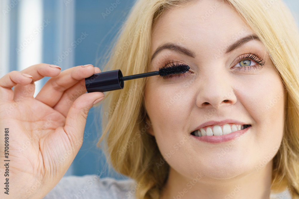 Woman using mascara on her eyelashes Woman using mascara on her eyelashes