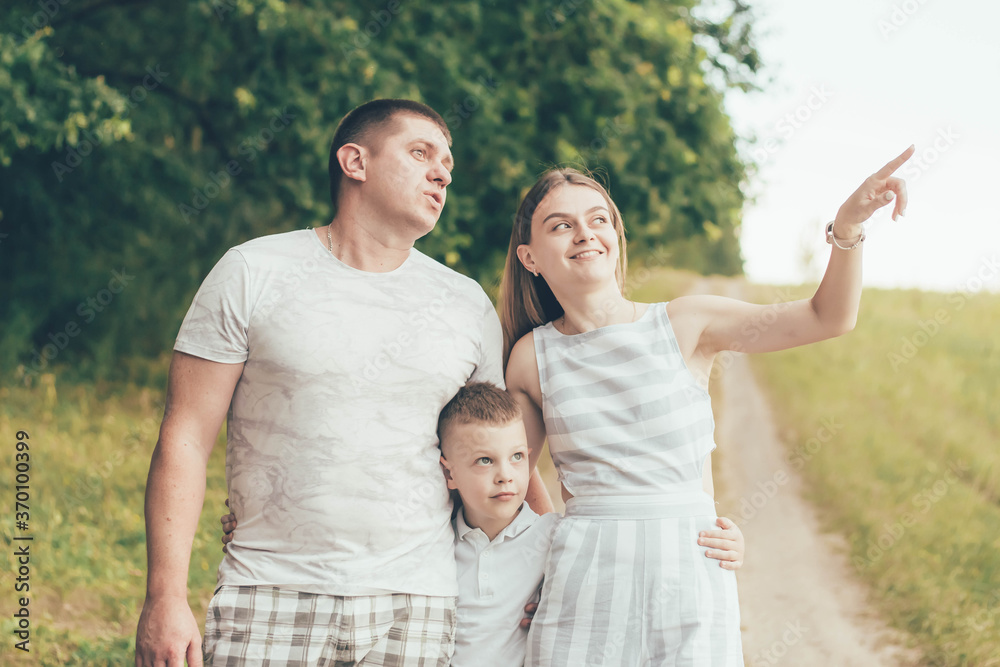 Obraz premium Family being in nature mom and dad hug son mom shows her hand to the sky and everyone looks