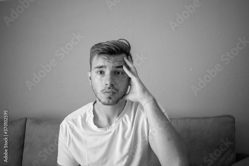 Black and White, Handsome man wearing a t-shirt and looking so confused and regret hitting his forehead with his hand, standing over isolated over a green background