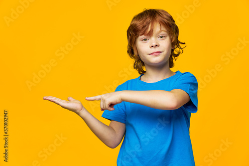 red-haired boy on a yellow background points his finger to the side and free space 