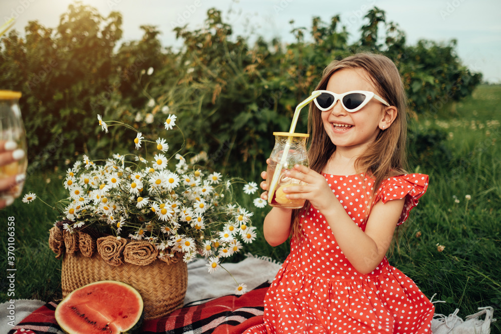 Fototapeta premium Beautiful Young Girl Dressed in Red Polka Dot Dress, Having Fun Time on a Picnic in the Field, Childhood Concept