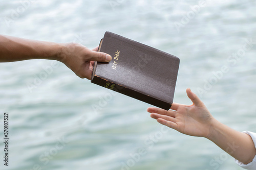 Man hand giving the Bible to women.Concept of giving