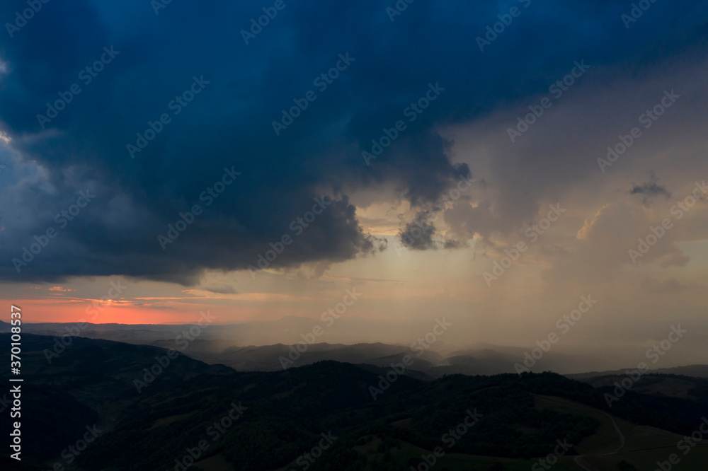Drone view of epic sunset with rainy clouds in Transylvania, Romania.