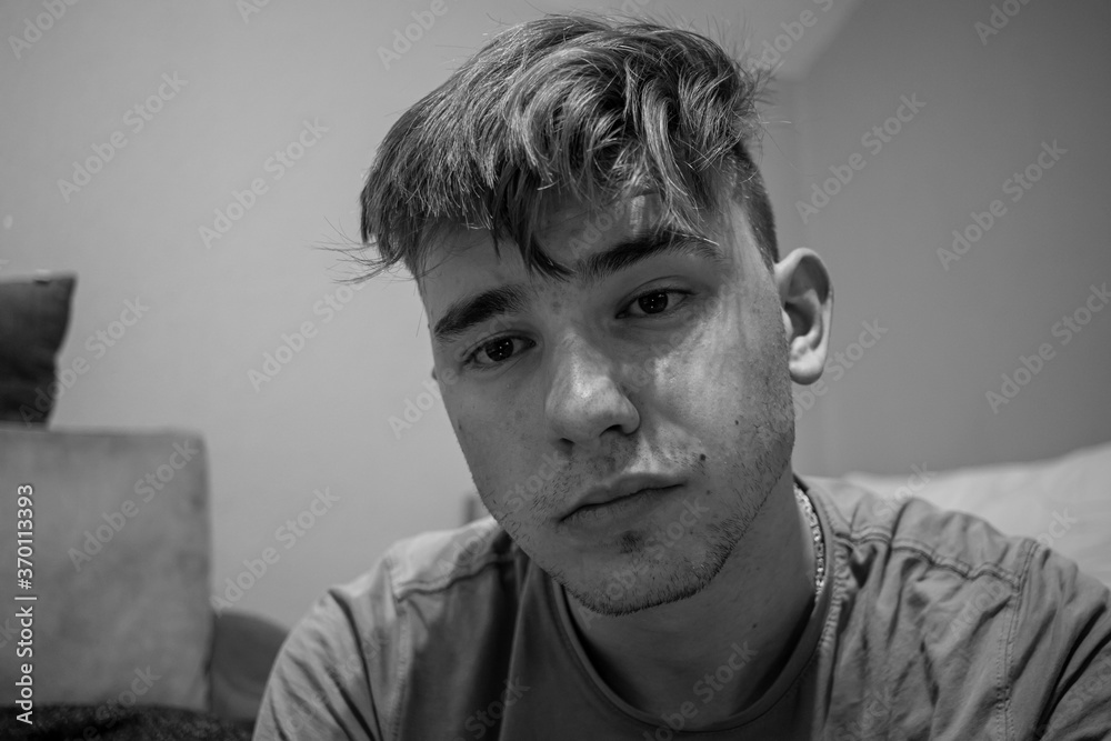 Fototapeta premium Young male with light brown hair looking interested in what the other person is talking to him in a green bedroom