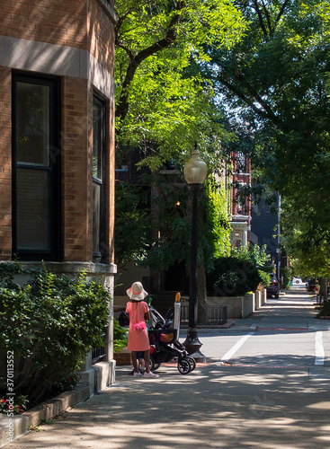 little girl in dress with brimmed hat and stroller on city street