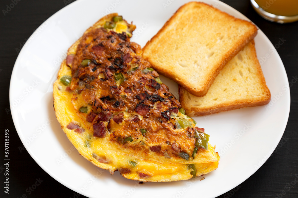 Homemade Denver Omelette on a white plate on a black background, side view. Homemade Denver Omelette on a white plate on a black background, side view.