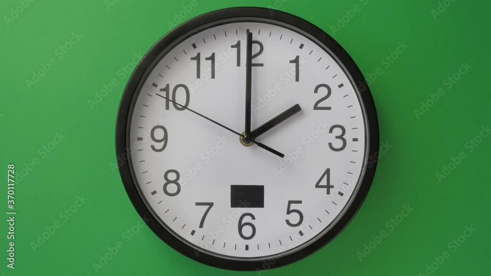 Single white office clock hanging on green background Single white office clock hanging on green background
