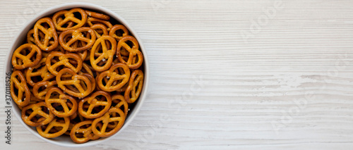 Crispy Pretzel Crackers in a Gray Bowl on a white wooden background, top view. Flat lay, overhead, from above. Space for text.