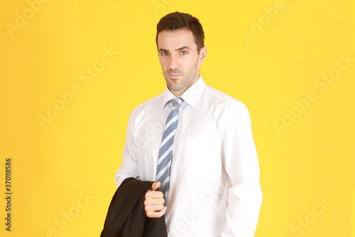 Handsome and smart businessman in suit and white shirt relaxing on isolatred on yellow background. Copy Space