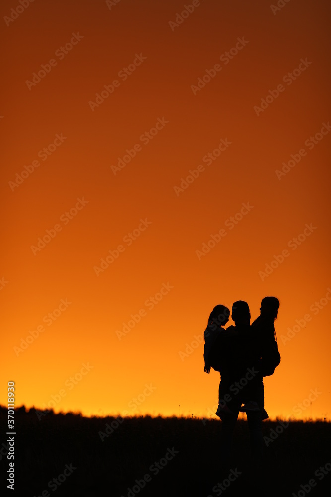 
beautiful sunset orange sky girls and dad happiness holding girls in his arms family