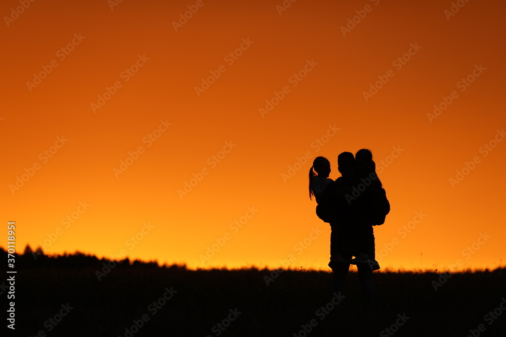 
beautiful sunset orange sky girls and dad happiness holding girls in his arms family