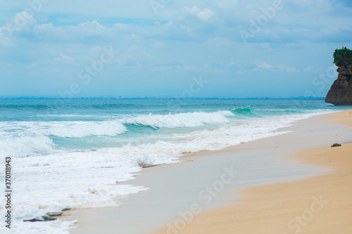 An ideal tropical sandy beach for surfing on the ocean. Beautiful clear turquoise water and waves.