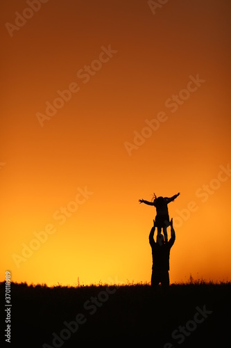 
beautiful sunset orange sky girl and dad happiness holding a girl in his arms family
