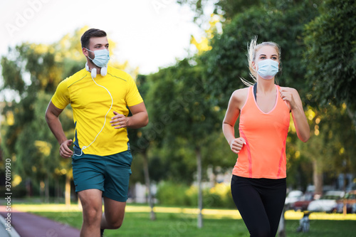 Young couple is jogging with protective masks. Covid-19 responsible behavior. © djoronimo