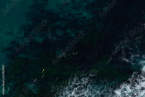 abstract blue background, surfers sitting in the ocean, view from above, aerial view